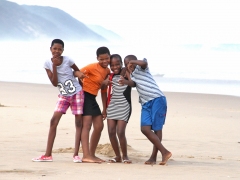 Några glada skolflickor poserar vid stranden.